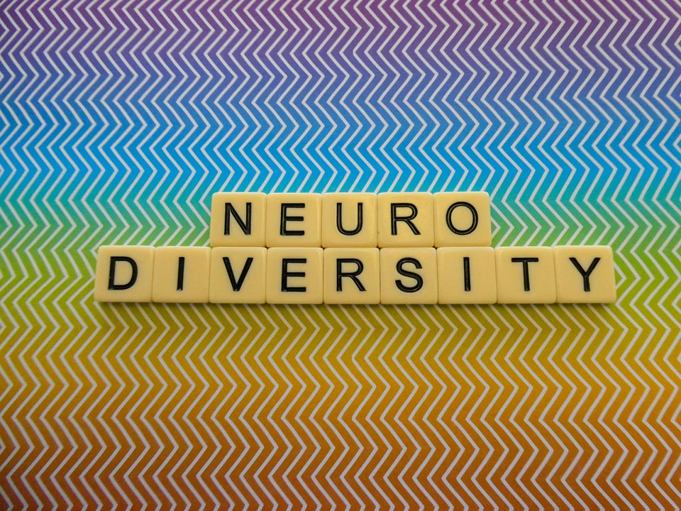 Bright rainbow zig zag pattern background sign with the word "NEURODIVERSITY"