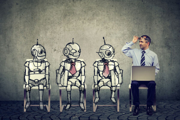 Three artistically drawn robots sitting next to an office man with a laptop