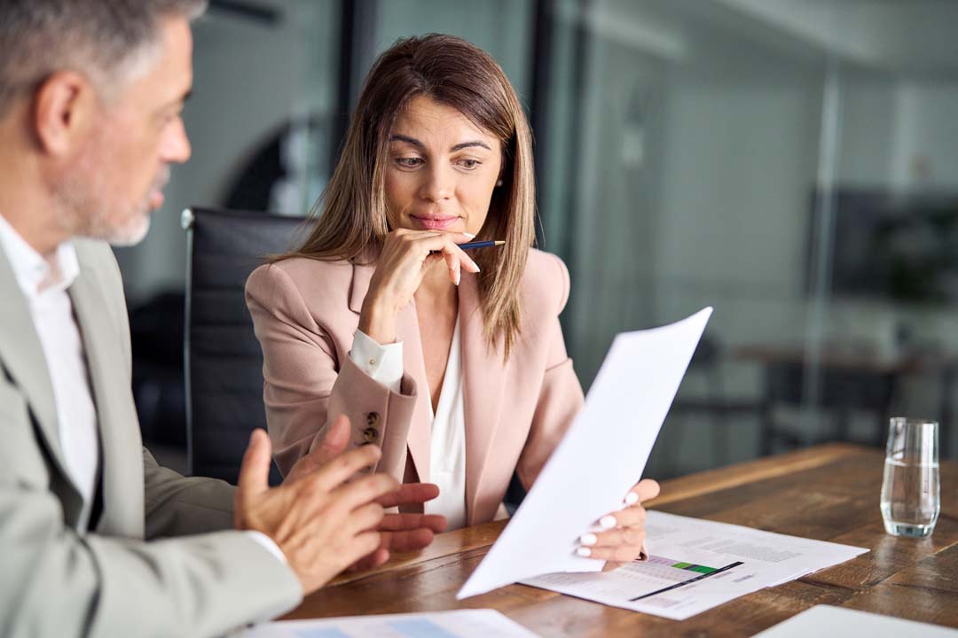 Two work people discussing and looking at a document.