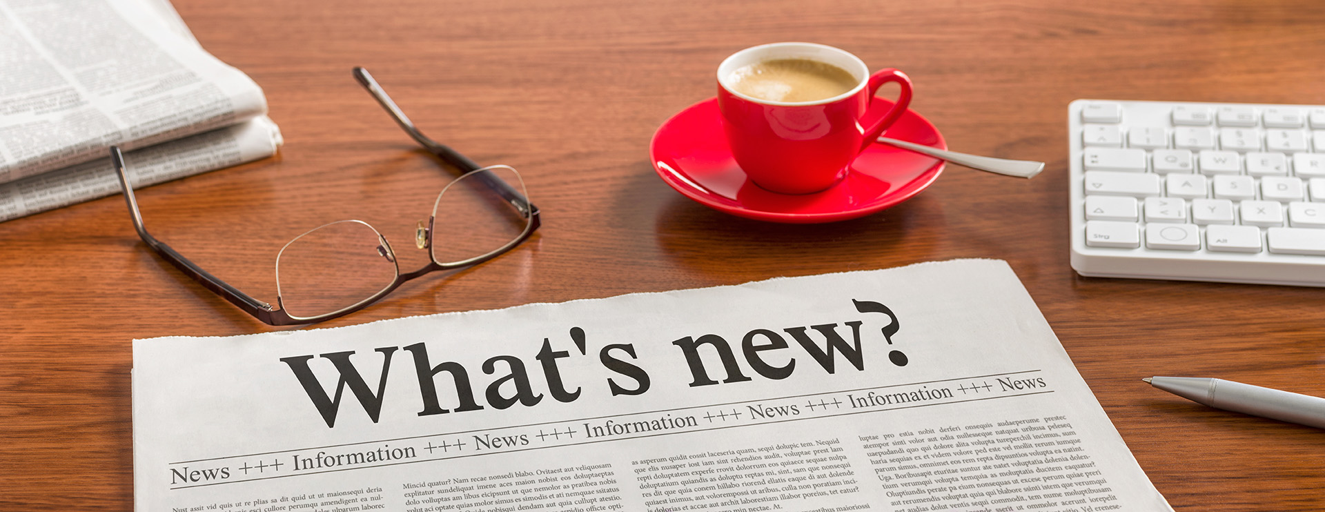 Newspaper heading of "What's new" with reading glasses and coffee cup