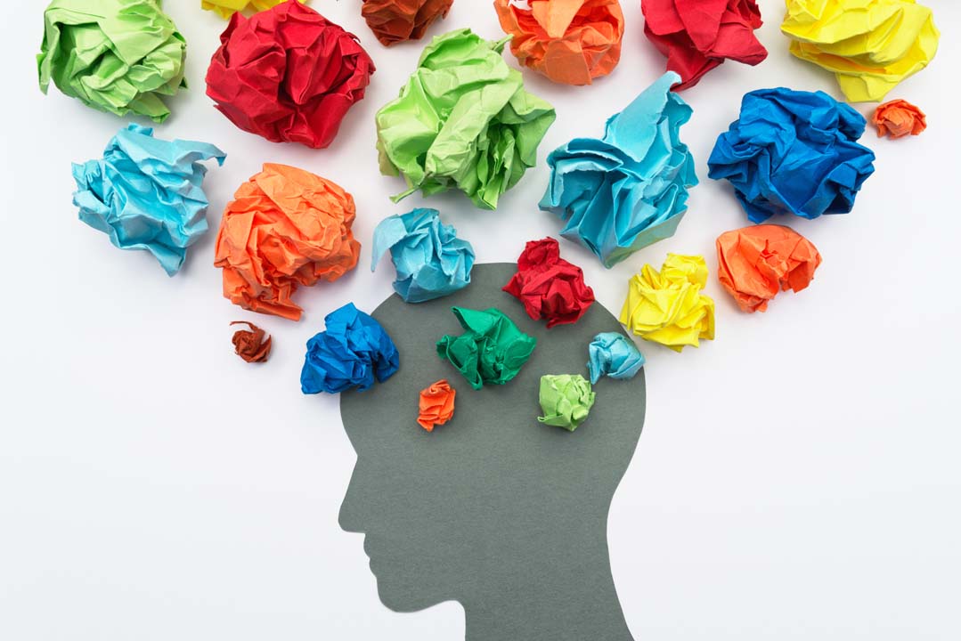 Image depicting mental health - a silhouette of a head with scrunched up colourful paper coming from the brain area.