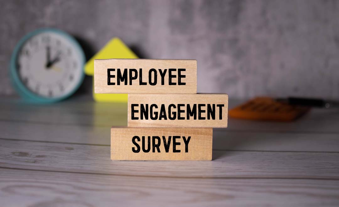 Office desk with wood blocks with text that states Employee Engagement Survey.