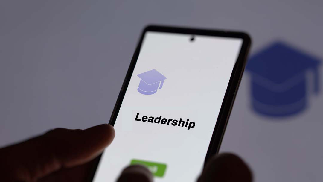 Mobile phone being held, with the word "leadership" on the screen.