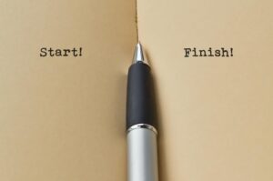 Open paper notebook with pen, with the words, start and finish on two different pages.
