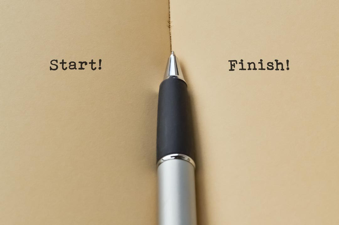 Open paper notebook with pen, with the words, start and finish on two different pages.