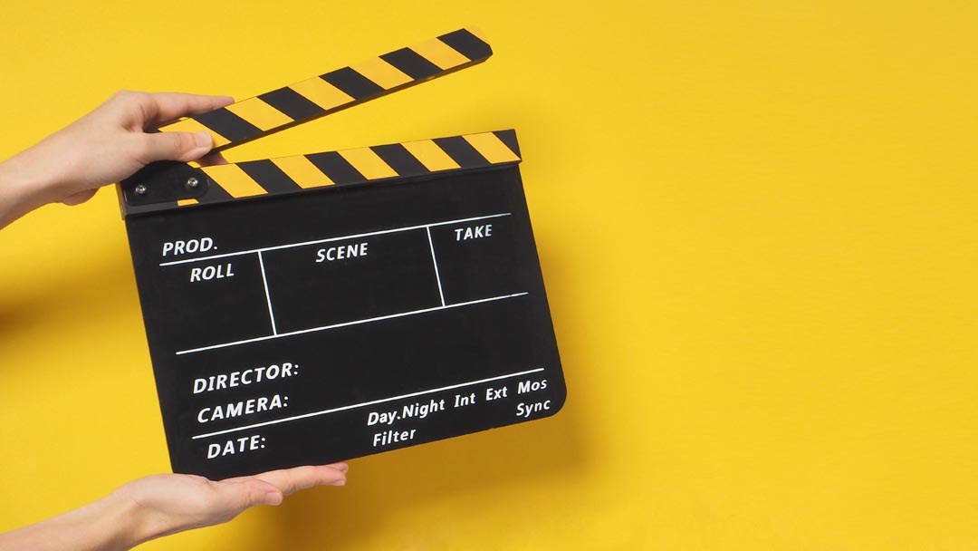 Hand is holding clapper board or clapperboard or movie slate on a yellow background.