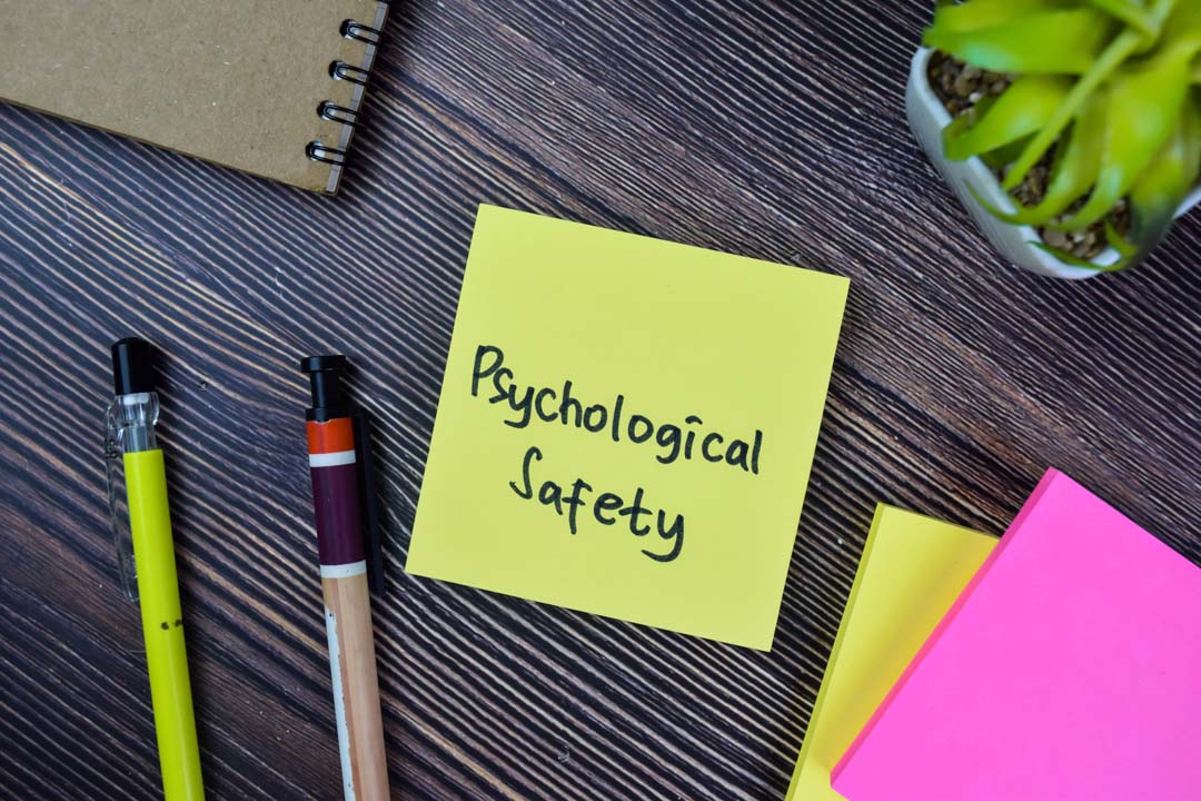 Yellow post-it note on a desk with "psychological saftey" written on it.