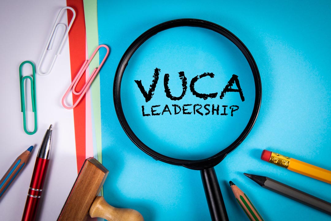 VUCA Leadership. Volatility Uncertainty Complexity Ambiguity. Magnifying glass on office desk.