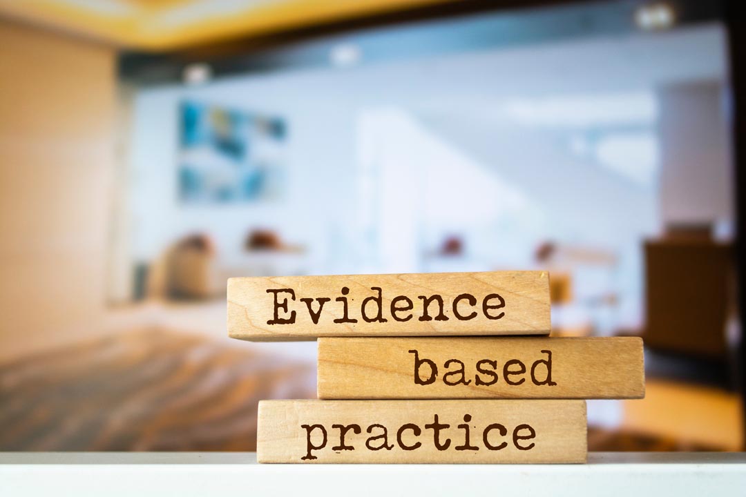 Wooden blocks with "evidence based practice" written on them with a corporate background.