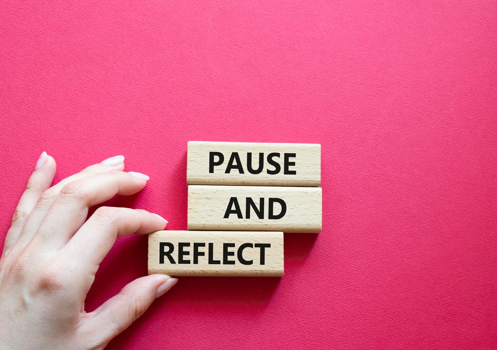 Words Pause and Reflect on wooden blocks. Beautiful red background.