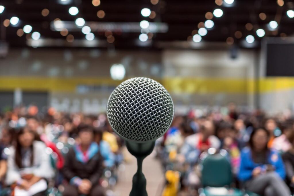 Microphone over the blurred photo of conference hall or seminar room