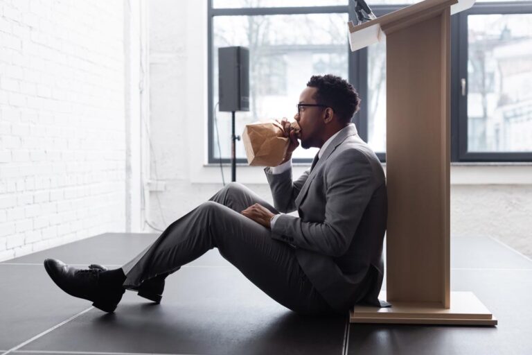 Nervous African american speaker breathing with paper bag and having panic attack during business conference.