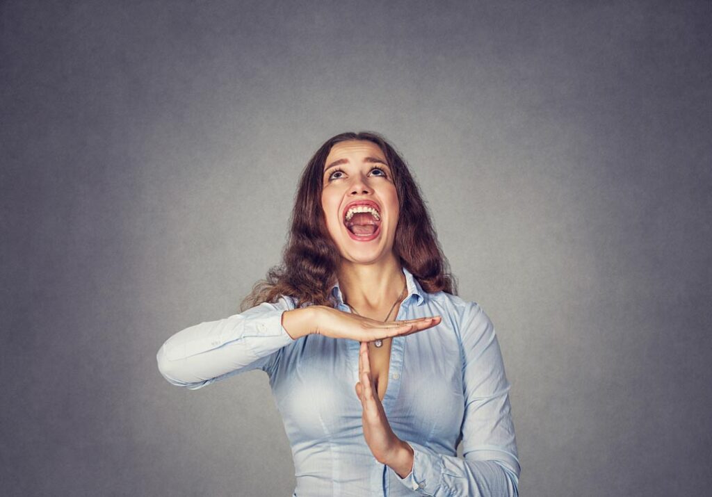 Brunette woman showing time out hand gesture, screaming to stop it.