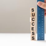 Measure success word using blue ruler, representing a review, evaluation or assessment of an employee