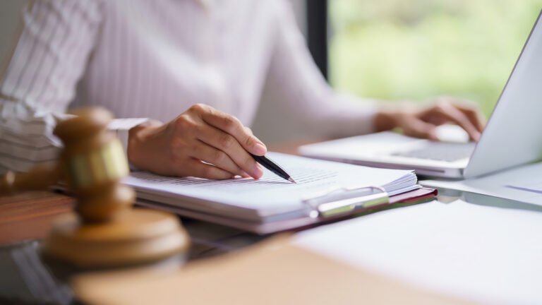 Lawyer woman reading and checking legal agreement of business contract to typing data on laptop