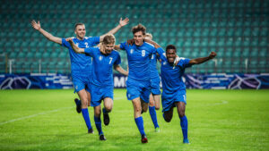 Soccer Football Championship: Blue Team Forward Attacks and Scores Goal, Win the Match, Players Happy, Celebrate Victory, Win Tournament. Sport Channel Broadcast Television Concept.