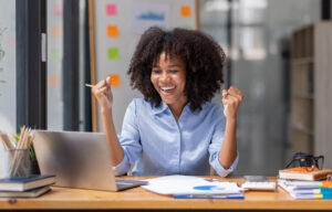 Excited african American woman sit at desk feel euphoric win online lottery, happy black woman overjoyed get mail at tablet being promoted at work, biracial girl amazed read good news at computer