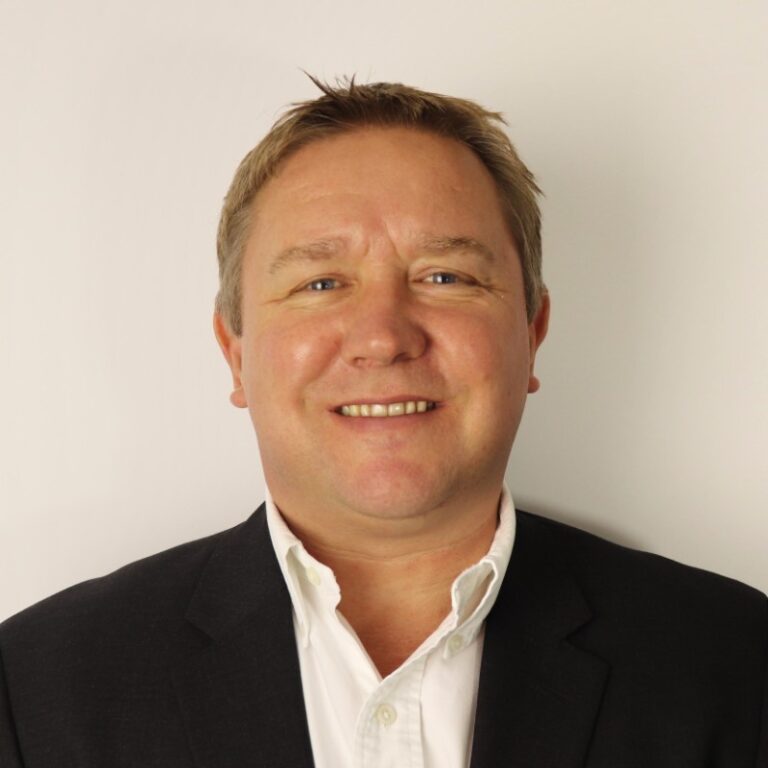Matt Webb headshot - white male wearing a suit, smiling at camera