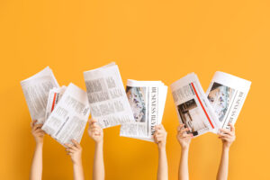 Female hands with newspapers on color background
