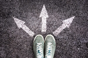 Sneakers shoes and arrows pointing in different directions on asphalt floor, life and studies choice for young people concept