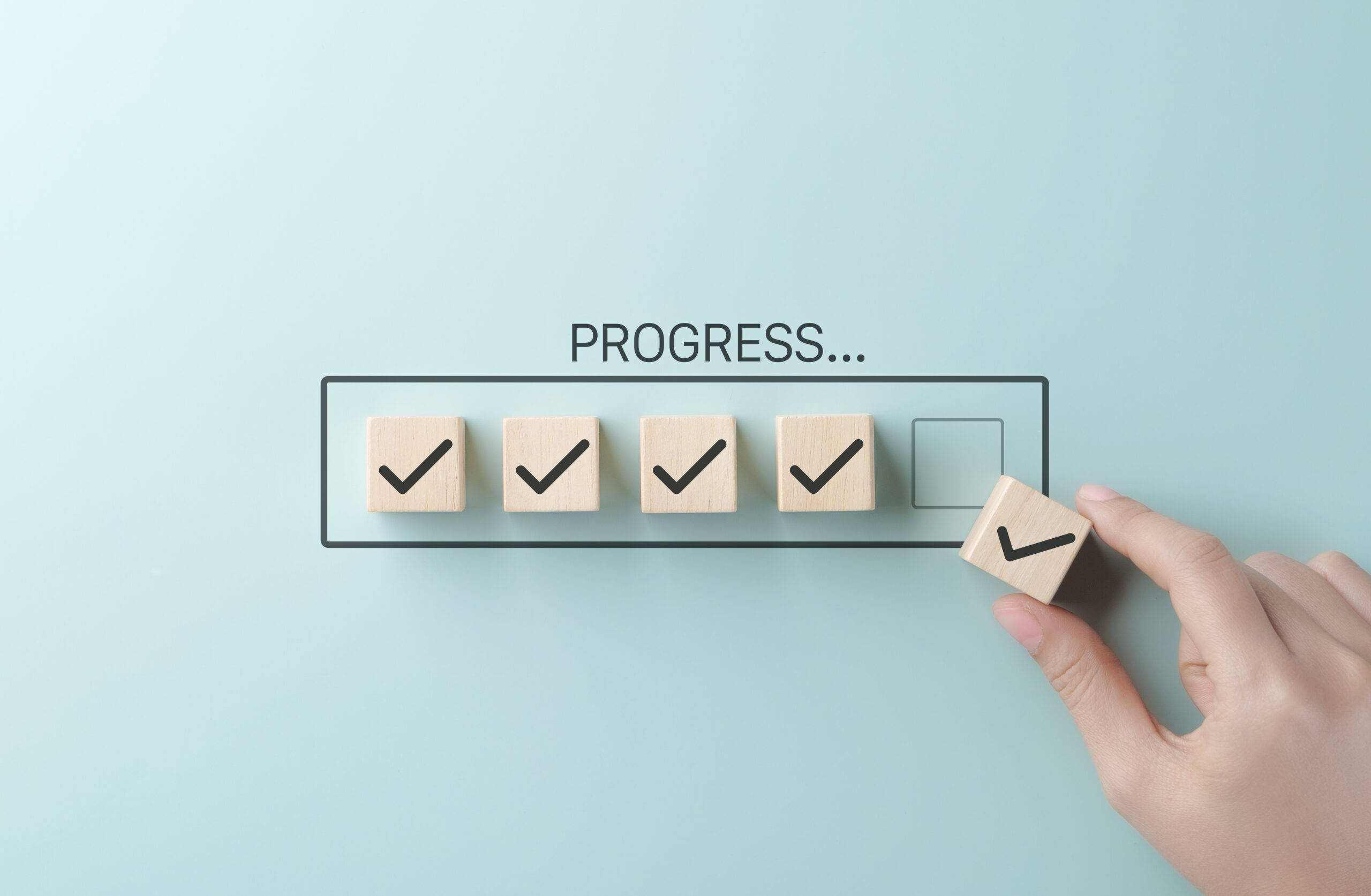 Checklist and task progress tracking concept. A hand placing the final checkmark on wooden blocks in a progress bar, task completion, productivity, goal setting, and efficient project management.