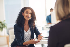 Interview with a happy, excited and confident human resources manager talking to a shortlist candidate for a job. Young business woman meeting with a colleague or coworker in her office at work