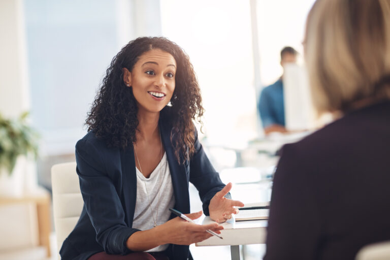 Interview with a happy, excited and confident human resources manager talking to a shortlist candidate for a job. Young business woman meeting with a colleague or coworker in her office at work