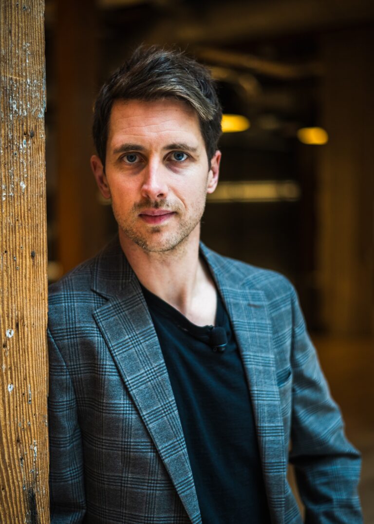Joseph Leslie - white man standing in a doorway, wearing a blue suit jacket.