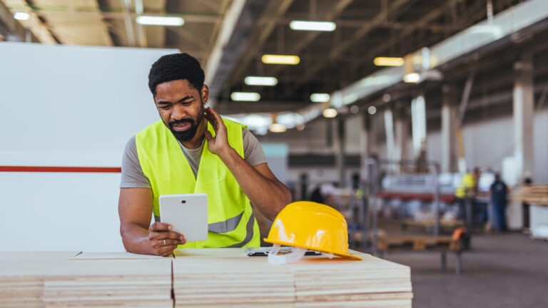 Construction Worker Using Tablet in Industrial Setting During Breaktime