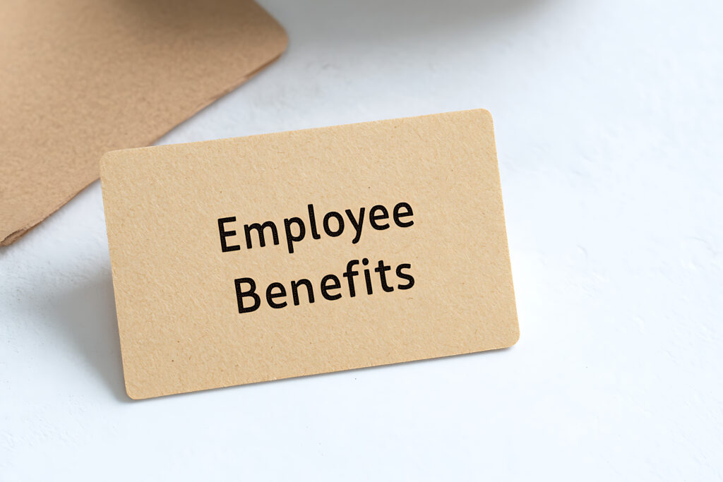 Paper card on a white surface showcasing text "Employee Benefits". Minimalist composition highlighting employment compensation and advantages.