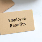 Paper card on a white surface showcasing text "Employee Benefits". Minimalist composition highlighting employment compensation and advantages.