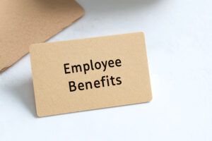Paper card on a white surface showcasing text "Employee Benefits". Minimalist composition highlighting employment compensation and advantages.