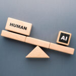 Wooden blocks on a seesaw showing human outweighing AI, symbolizing comparison between human capability and artificial intelligence in work and productivity