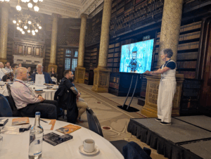 Business of Training Conference 2025 showing Stella Collins speaking on stage.