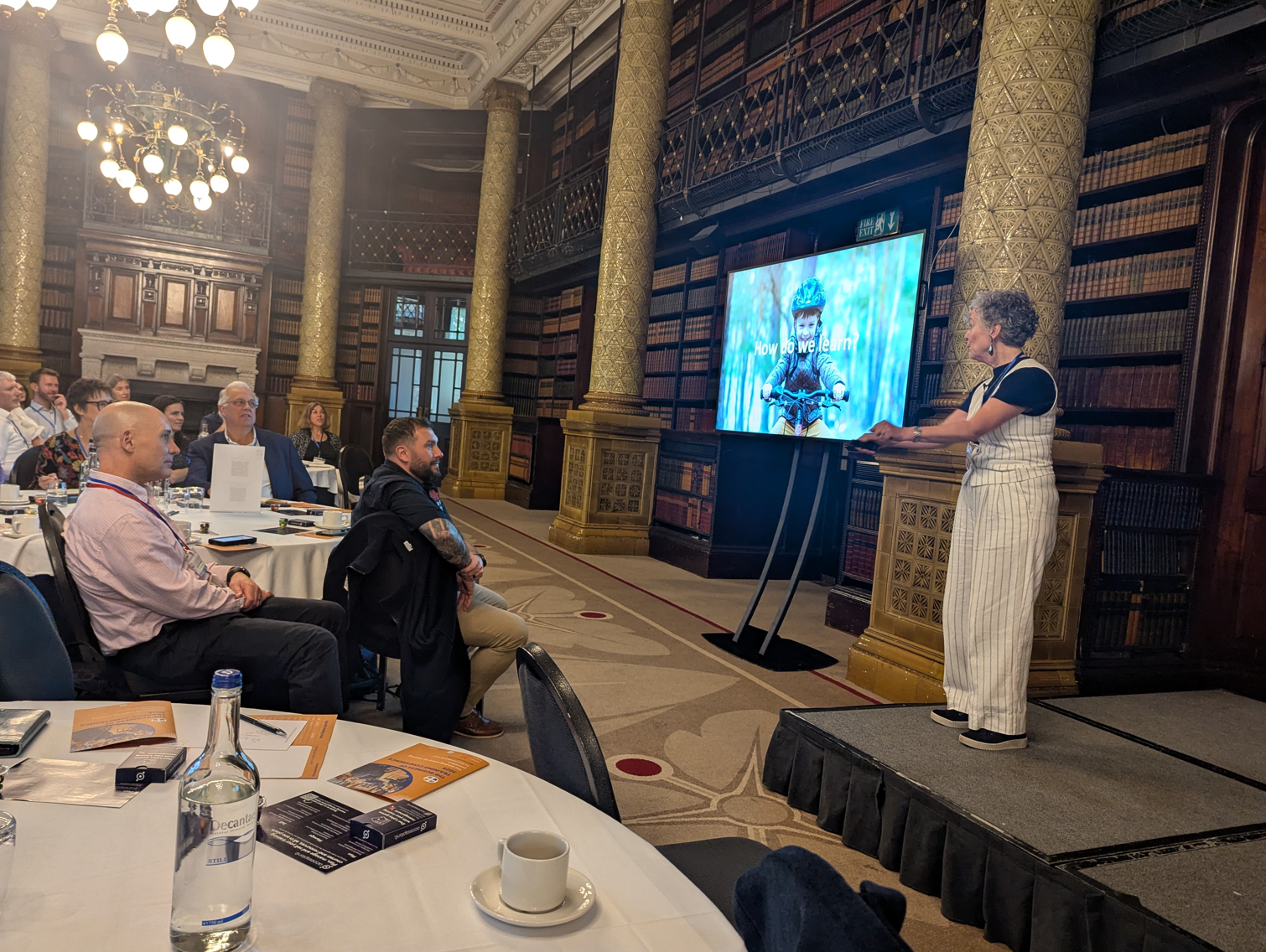 Business of Training Conference 2025 showing Stella Collins speaking on stage.