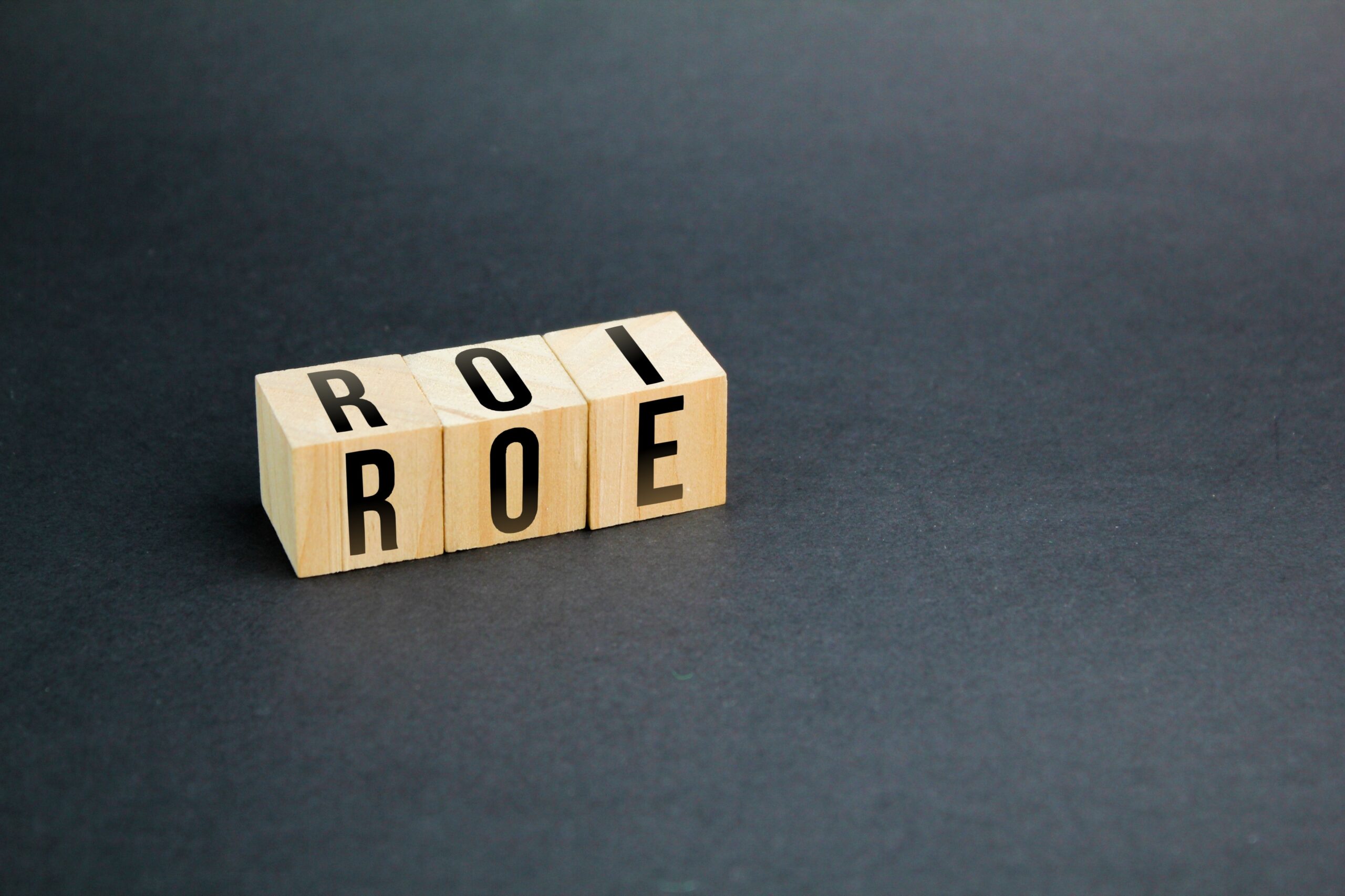 wooden cube with letters ROI and ROE. Return on Equity (ROE) vs. Return on Investment (ROI)
