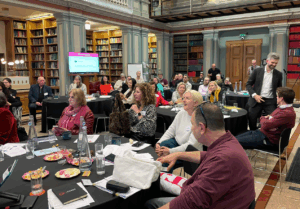 TJ 60th Anniversary conference library room with round tables and people attending