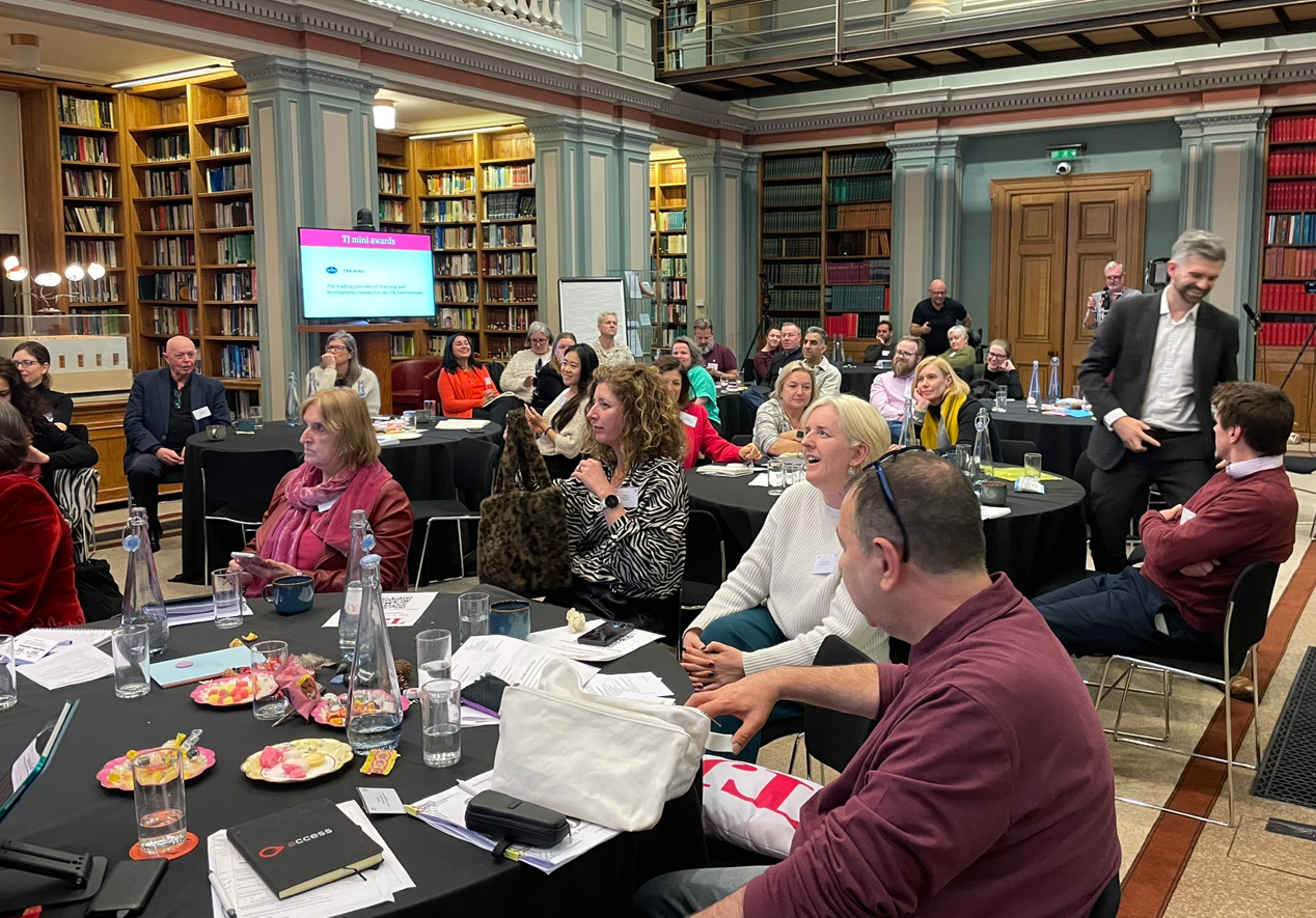 TJ 60th Anniversary conference library room with round tables and people attending