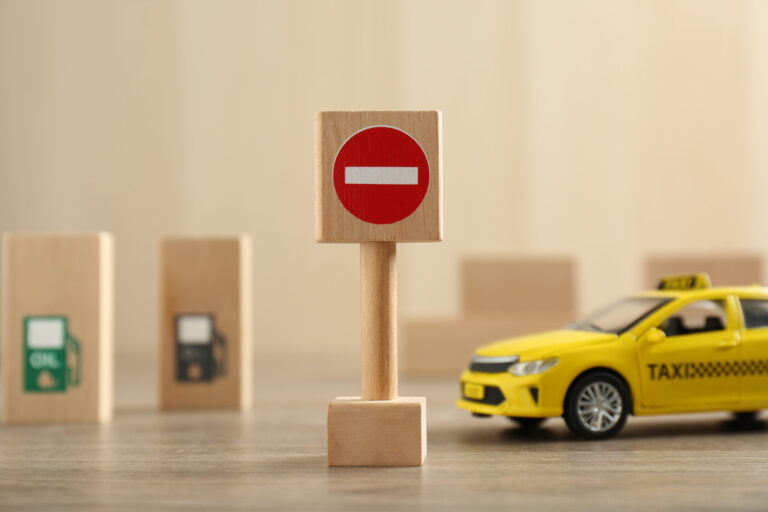 Traffic sign No entry and toy taxi car on wooden table. Passing driving license exam