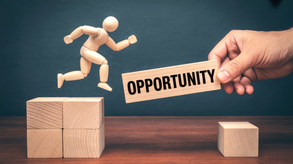 Wooden mannequin jumping across a gap while a human hand provides a bridge labeled Opportunity on a dark background