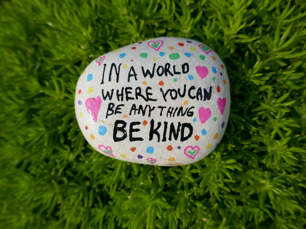 In a world where you can be anything be kind kindness rock on green moss