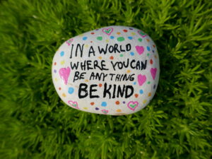 In a world where you can be anything be kind kindness rock on green moss