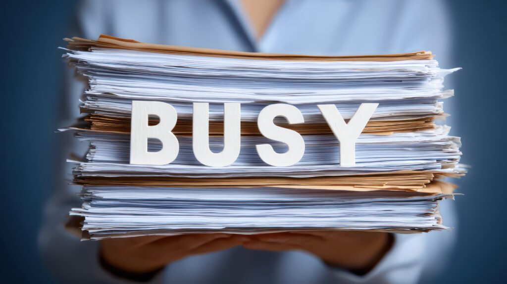 Overwhelmed Worker with 'Busy' Paperwork Stack