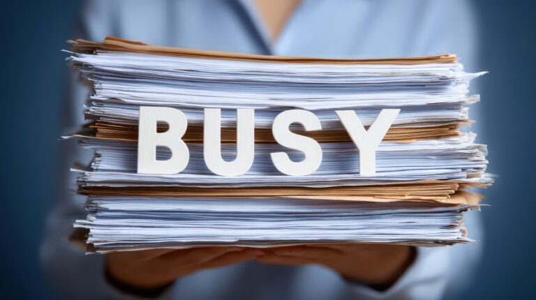 Overwhelmed Worker with 'Busy' Paperwork Stack