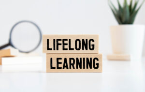 Finance concept.Text Lifelong learning on colorful paper note with calculator and pencil on black background