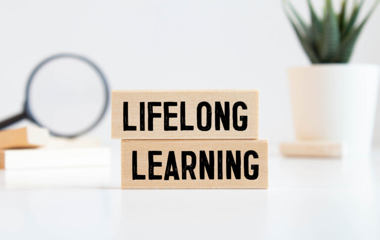 Finance concept.Text Lifelong learning on colorful paper note with calculator and pencil on black background