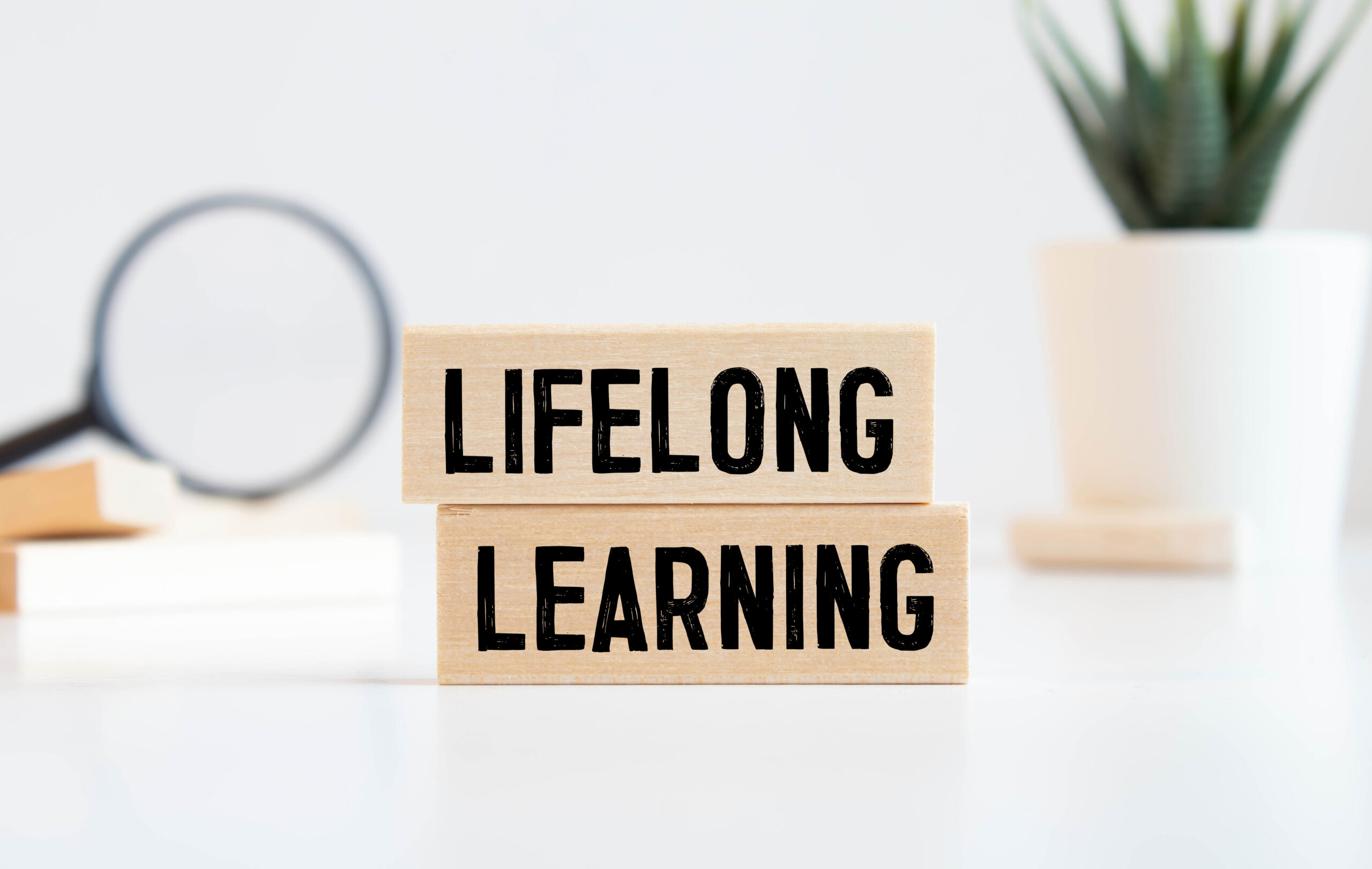 Finance concept.Text Lifelong learning on colorful paper note with calculator and pencil on black background