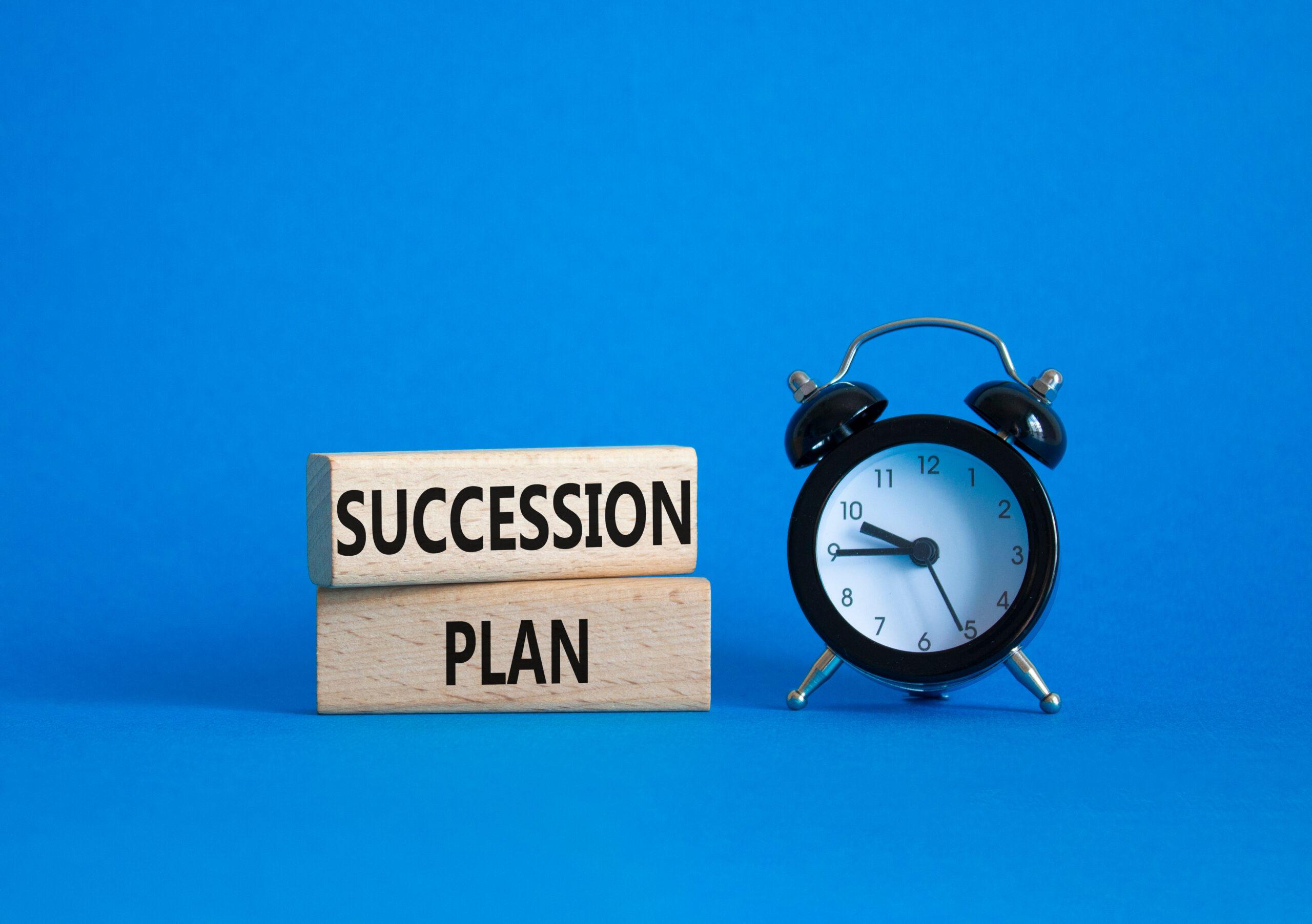 Succession Plan symbol. Wooden blocks with words Succession Plan. Beautiful blue background with alarm clock. Business and Succession Plan concept. Copy space.