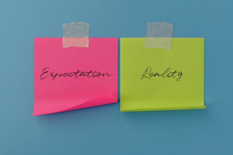 Two sticky notes with handwritten Expectation and Reality. Business results, comparison, performance evaluation, and strategic planning concept.