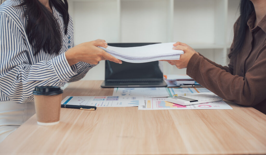 Handing Over: A collaborative office scene as one individual hands over documents to another, fostering seamless teamwork and efficient communication.